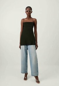 Must räbidega büstik, mis on paaritatud helesiniste laiadest pükstest ja läbipaistvatest kontsadest, ning täiendab valged prillid.