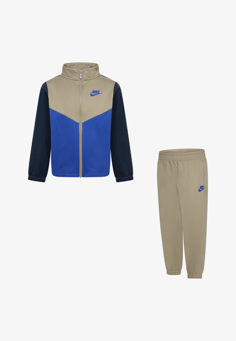 Fato de treino Nike com um casaco com fecho éclair em design de blocos de cor bege, azul e azul-marinho, emparelhado com calças de cintura elástica bege.