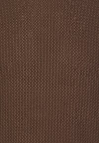 Tissu en maille marron avec un motif en zigzag texturé, offrant une sensation douce et respirante ainsi qu'un tissage uniforme et constant sur toute la surface.