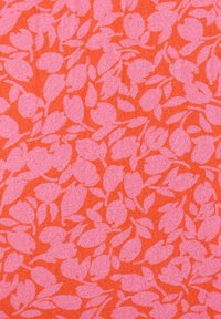 Květinový vzor látky s malými růžovými listovými tvary na oranžovém pozadí. Textura působí hladce a mírně strukturovaně.