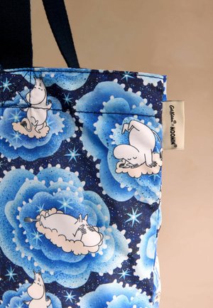 Tote krepšys su mėlynu gėlių raštu ir baltais Moomin personažais. Medžiaga - blizgus audinys su tamsiai mėlynomis petnešomis ir prekės ženklu.