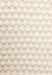 Gros plan sur un tissu tricoté de couleur crème avec un motif doux et texturé de petites clusters en relief et de points entrelacés.