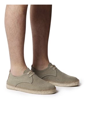 Beige canvas sko med lavt design, snørebåndslukning og kontrasterende syninger; espadrille-stil jute sål for tekstur.