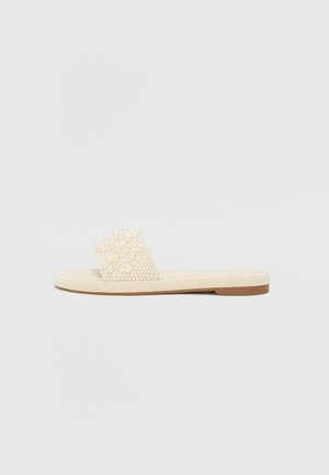 Sandal de slide bege com uma tira texturizada coberta de pequenos enfeites semelhantes a pérolas; sola plana com um acabamento suave.