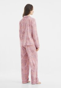 Rosa Schlafanzug-Set mit einem wiederholten Frühstücksmuster. Hergestellt aus weichem Stoff mit einem lässigen Schnitt, bestehend aus einem kragenlosen Oberteil und passenden Hosen.