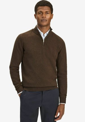 Brun zip-up sweater lavet af blødt materiale med ribbede manchetter og nederkant. Båret over en lys blå skjorte med krave, som har et klassisk design.