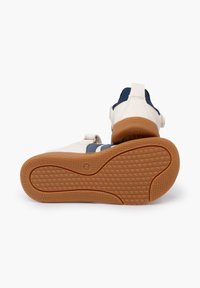 Scarpe sportive bianche con strisce blu navy, suola in gomma testurizzata, cinturino regolabile in Velcro e suola esterna marrone a contrasto. Presentano una tomaia in morbida pelle.