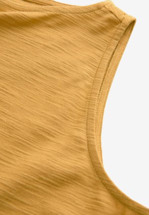Top senza maniche color giallo senape realizzato in un morbido tessuto testurizzato. Caratterizzato da un collo tondo e da cuciture pulite e discrete lungo i bordi.