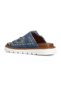 Sandalo in denim con bordo frangiato, borchie dorate, soletta in pelle marrone e suola in gomma bianca spessa con texture rigata.