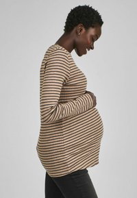 Gestreiftes langärmliges Umstandsshirt in Beige und Dunkelbraun, mit einer figurbetonten Passform, die einen runden Bauch betont und über eine gerippte Textur verfügt.