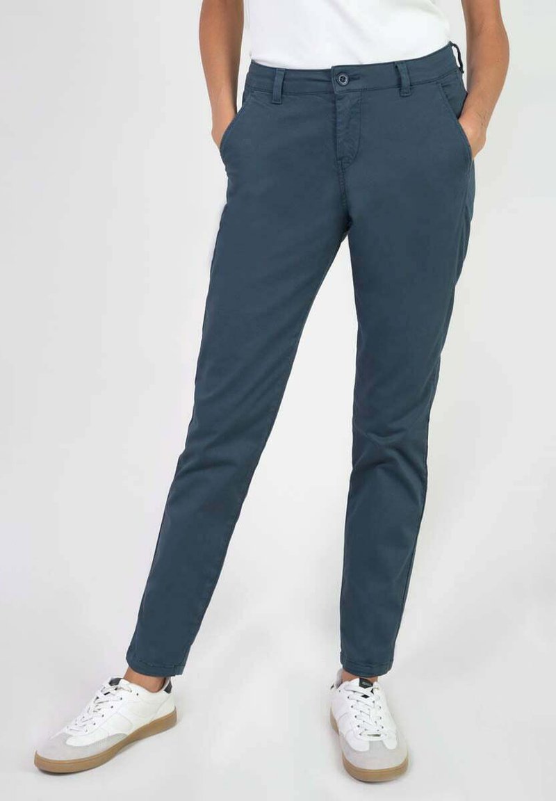 Pantalons chino en coton bleu marine avec une coupe slim, dotés de poches avant, d'une fermeture à bouton et d'une texture lisse. Portés avec des baskets blanches.