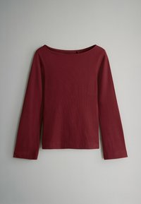 Burgundská dlhá rukávová blúzka s lodičkovým výstrihom. Vyrobená z ribovaného materiálu, má rovný lem a jednotnú textúru po celom obvode.
