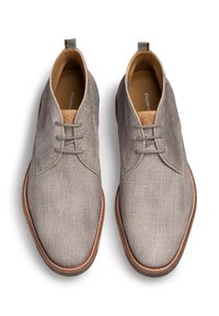 Graue Stoffschuhe mit glatter Textur, runder Zehenpartie und kontrastierenden braunen Lederakzenten. Verfügt über ein Schnürdesign und eine Schlaufe zum Hochziehen.
