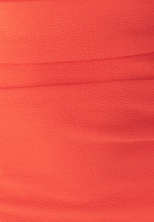 Korálová zmačkaná tkanina s texturovaným povrchem. Materiál je lehký a obsahuje vodorovné sklady, které přidávají rozměr a vizuální zajímavost.