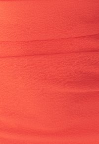 Korallenfarbener, gekräuselter Stoff mit strukturierter Oberfläche. Das Material ist leicht und weist horizontale Falten auf, um zusätzliche Dimension und visuelles Interesse zu schaffen.