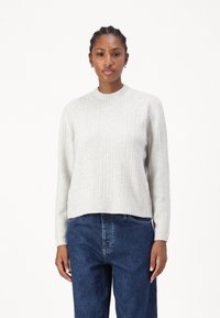 Lys grå, teksturert genser med ribbestrikket rund hals og vertikale mønstre. Kombinert med mørkeblå, løstsittende jeans.
