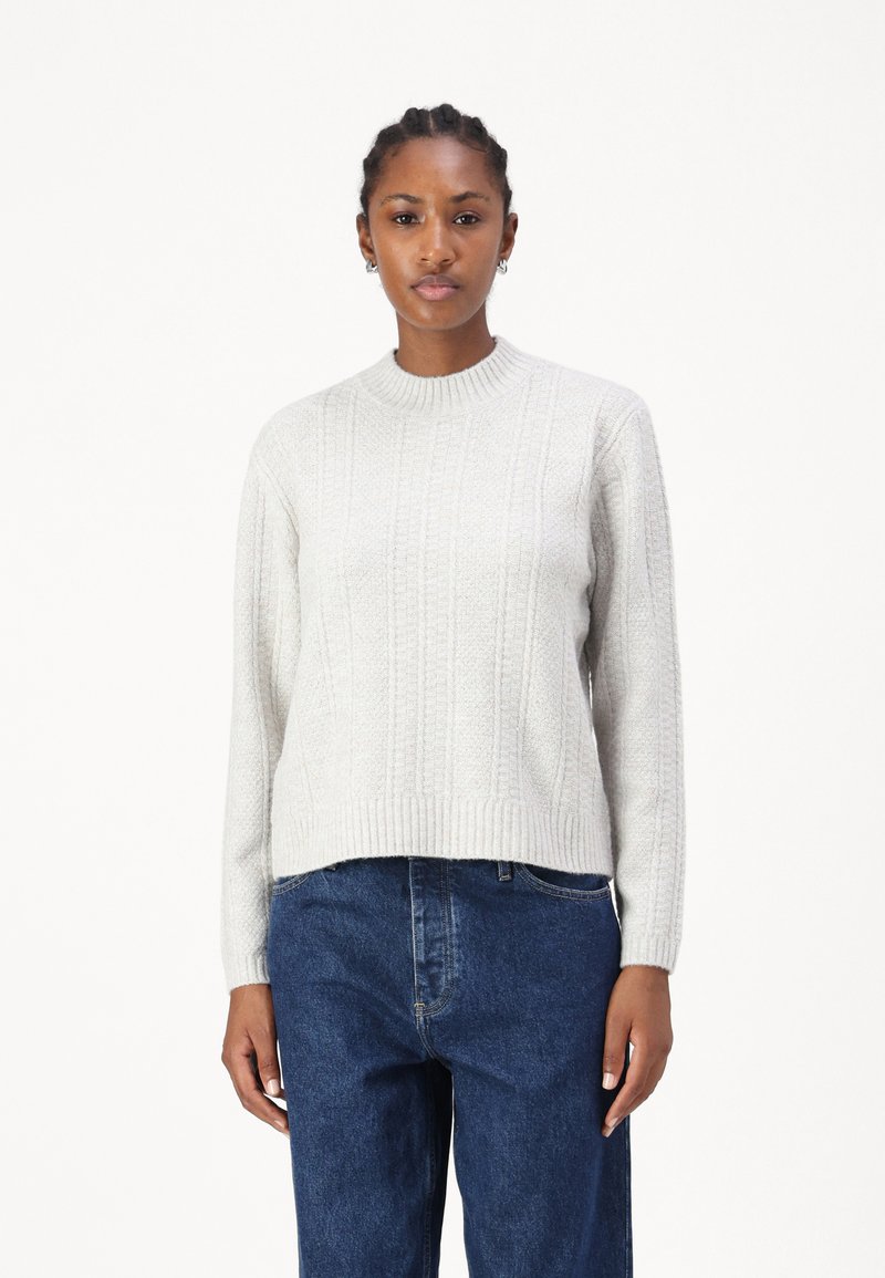 Lys grå, teksturert genser med ribbestrikket rund hals og vertikale mønstre. Kombinert med mørkeblå, løstsittende jeans.