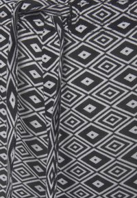 Black and white drawstring shorts with a geometric diamond pattern, made from soft fabric featuring a textured finish.