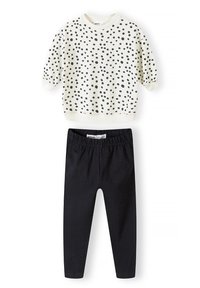 Lys cremet sweatshirt med sorte prikker og korte ærmer, kombineret med sorte stræk leggings. Blødt bomuldsstof, afslappet pasform.