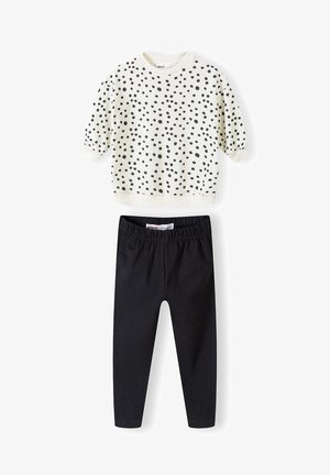 Helle Creme Sweatshirt mit schwarzen Punkten und kurzen Ärmeln, kombiniert mit schwarzen Leggings aus dehnbarem Stoff. Weicher Baumwollstoff, lässige Passform.