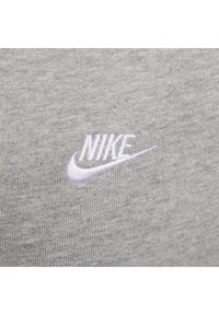 Tejido gris con un patrón texturizado que presenta un logo bordado de Nike en blanco en el lado izquierdo. Diseño sencillo y limpio.
