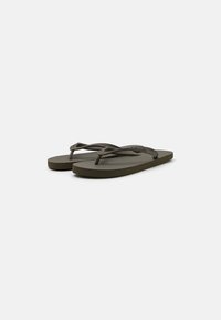 Oliven grønn flip-flops lavet af gummi med en tekstureret stropp og flad sål, der har et logo på fodsengen og et enkelt design.