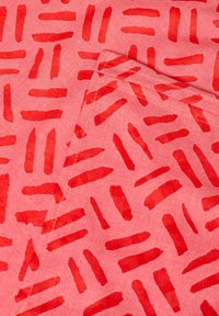Tessuto con motivo rosso caratterizzato da disegni a pennellate orizzontali e verticali su uno sfondo rosa chiaro. Aspetto audace e strutturato.