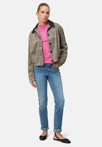 Károvaná bunda s černým límcem, pod ní růžový svetr, světle modré džíny a černé boty. Texturovaná látka a střih na míru.