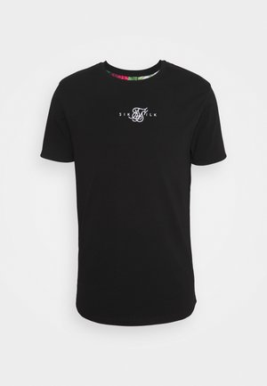 Black cotton t-shirt featuring a crew neckline and short sleeves. Front displays white logo text; inside collar has floral print detail.