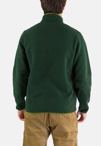 Chaqueta de forro polar verde oscuro con un cuello alto y un ribete en un verde claro contrastante, que presenta una textura suave y un diseño simple.