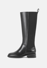 Botas pretas até ao joelho, feitas de couro liso, com painéis laterais elásticos, salto plano e puxador na parte de trás para facilitar o calçar.