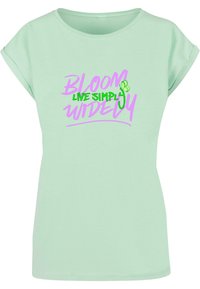 Mintgrøn T-shirt med korte, rullede ærmer, der har et grafisk print i lilla og grøn, som siger "BLOOM LIVE SIMPLY WIDEY."