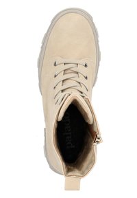 Botín beige hasta el tobillo, hecho de gamuza suave, con punta redondeada, frente con cordones, cuello acolchado, suela gris y cremallera lateral.