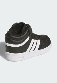 Černé vysoké tenisky vyrobené z kůže s bílými akcenty a designem tří pruhů. Obsahují texturovanou panel a bílou gumovou podrážku.