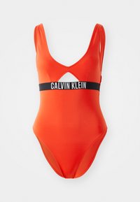 Červený jednodílný plavky s hlubokým V výstřihem, výřezem vpředu a černým pasem se textem "CALVIN KLEIN." Hladký materiál.
