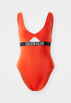 Červený jednodílný plavky s hlubokým V výstřihem, výřezem vpředu a černým pasem se textem "CALVIN KLEIN." Hladký materiál.