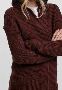 Burgundy knit cardigan with a hood. Features a textured pattern, long sleeves, and front pockets for added detail.