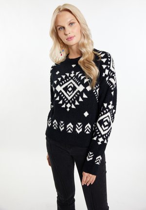 Pulover negru cu motive geometrice albe, textura pufoasă, guler rotund și mâneci lungi. Asortat cu pantaloni negri.