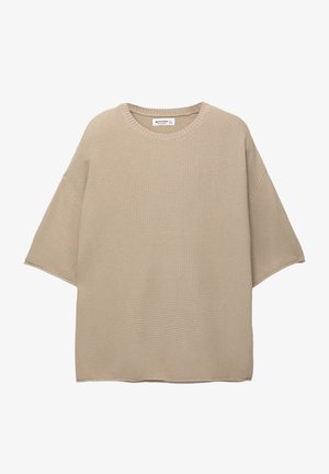 Pull beige surdimensionné en tricot texturé, avec un col rond et des manches courtes, présentant un ourlet droit simple.
