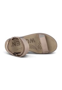 Beige sandal with adjustable straps, cushioned insole, and textured outsole. Features logo on the footbed and metallic accents.