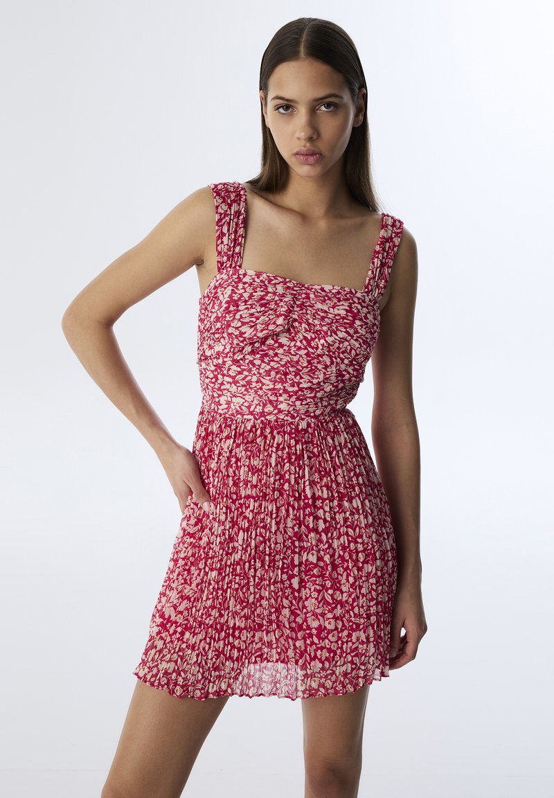 Rood bloemenpatroondress met een aansluitende bovenkant met plooien en vierkante halslijn, versierd met brede banden en een vloeiende rok.