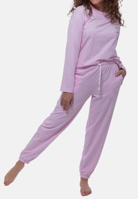 Ljusrosa långärmad topp med rund hals och avslappnad passform, parat med matchande lätta joggers med elastisk midja och fickor.