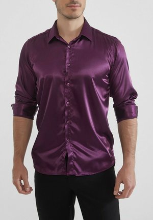 Chemise en satin violet à manches longues, avec un devant à boutons et des poignets retroussés. Texture lisse, design ajusté et col classique.