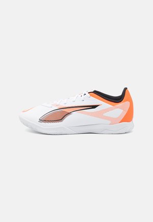White athletic shoe with orange and black accents. Features a textured upper, a sleek design, and a rubber sole for traction.
