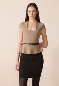 Béžový peplum top s krátkými rukávy, čtvercovým výstřihem a zvýrazněným pasem černým pásem, v kombinaci s přiléhavou černou sukní. Hladká textura látky.