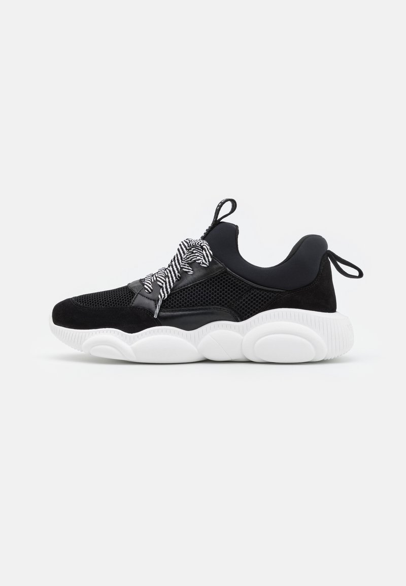 Baskets homme noir et blanc avec tige en mesh, semelle blanche épaisse, cheville rembourrée, lacets rayés et languettes au talon et à la languette.