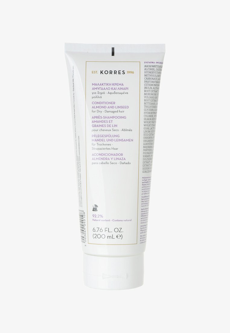 Vit tubbalsam med flip-lock. Har lila och guld accenter. Texten indikerar att den innehåller mandel och linfrö för torrt, skadat hår.