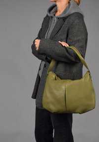 Olijfgroen leren handtas met een zachte, afgeronde vorm en een enkele schouderband. Heeft zichtbare stiksels en een ritsluiting.