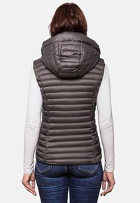 Donkergrijze gewatteerde puffervest met een grote capuchon. Kenmerkt zich door horizontale panelen en een gladde textuur, gedragen over een witte longslijfshemd.