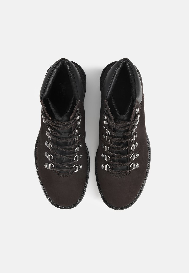 Bruine suède wandelschoenen met zwarte leren accenten, voorzien van zilveren ogen en veters, een ronde neus en een gestructureerde zool.